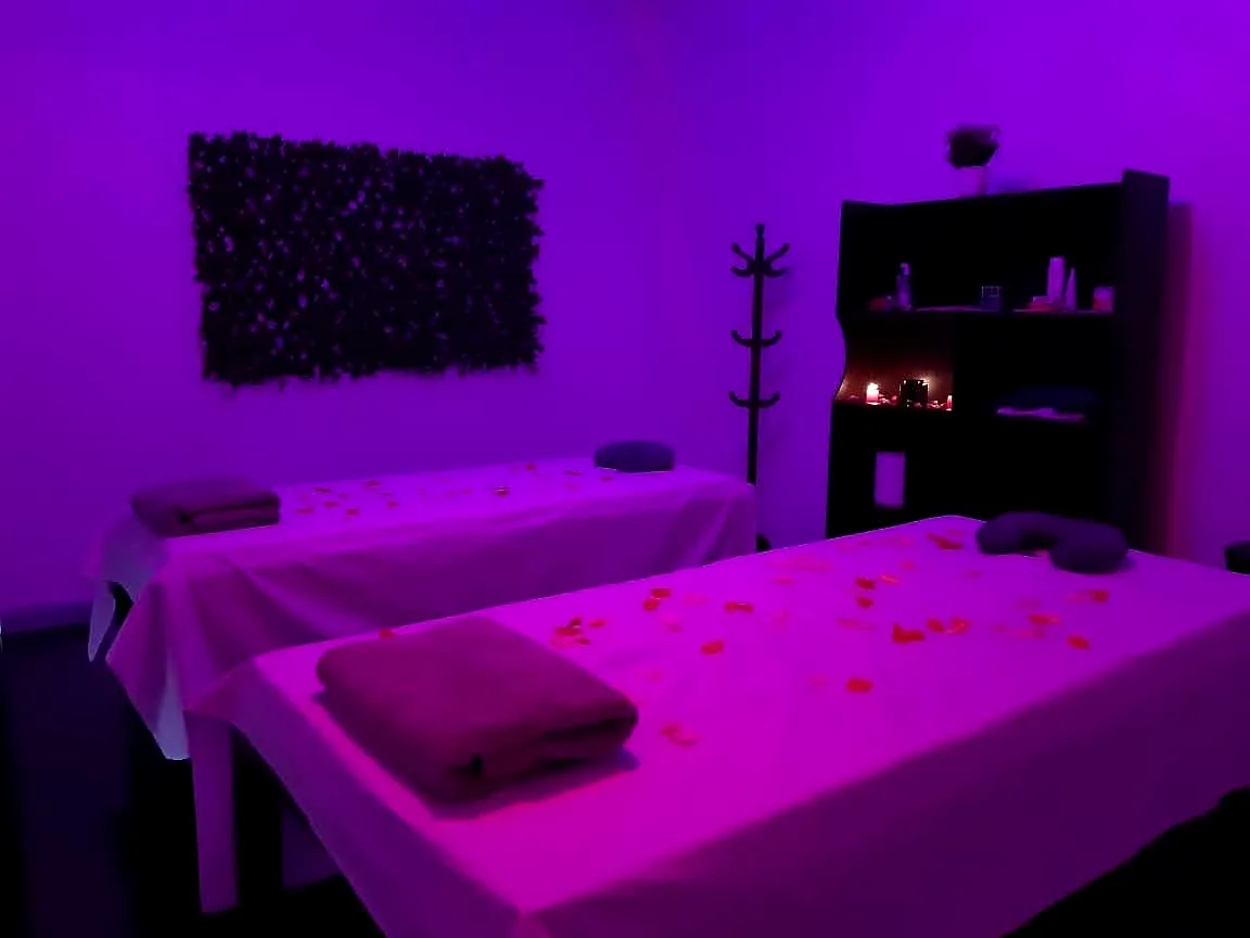 Sala de masajes para dos personas de Qoeurs Spa, ambientada con pétalos y velas
